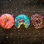 pink, blue, and chocolate with sprinkles doughnuts on table